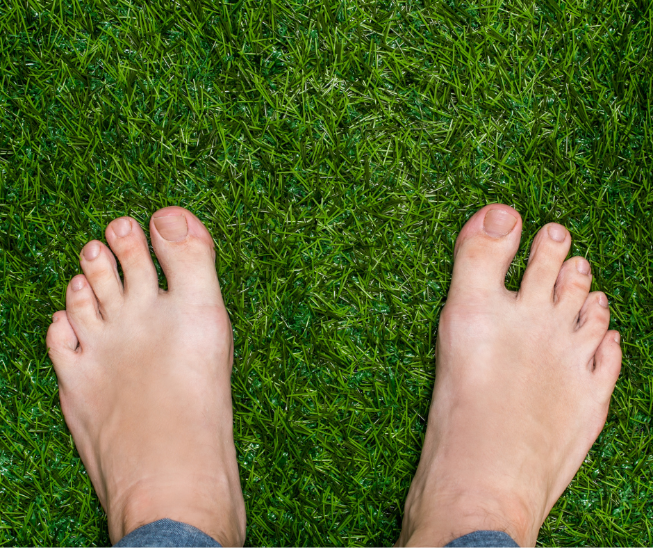 Välvårdade manliga fötter på grönt gräs.